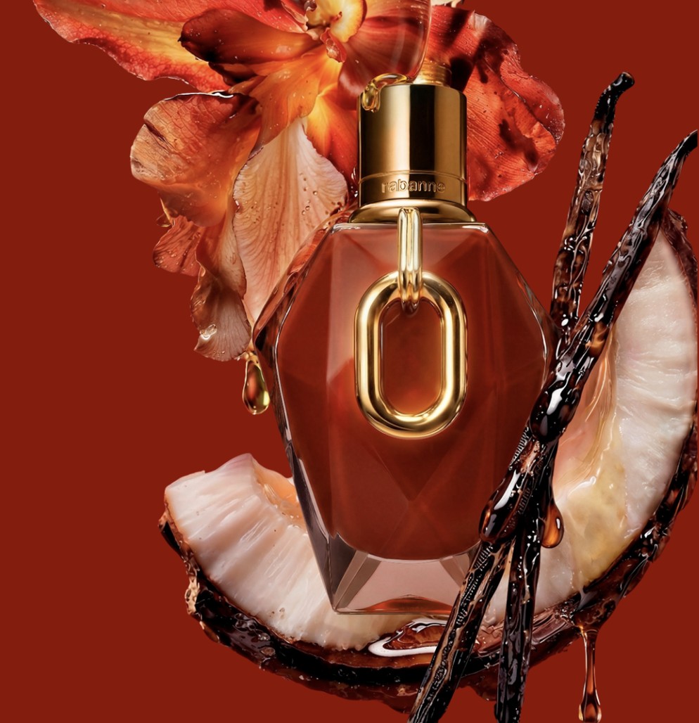 The red lacquered Million Red For Her Parfum bottle with a gold XL Link, surrounded by coconut and vanilla pods