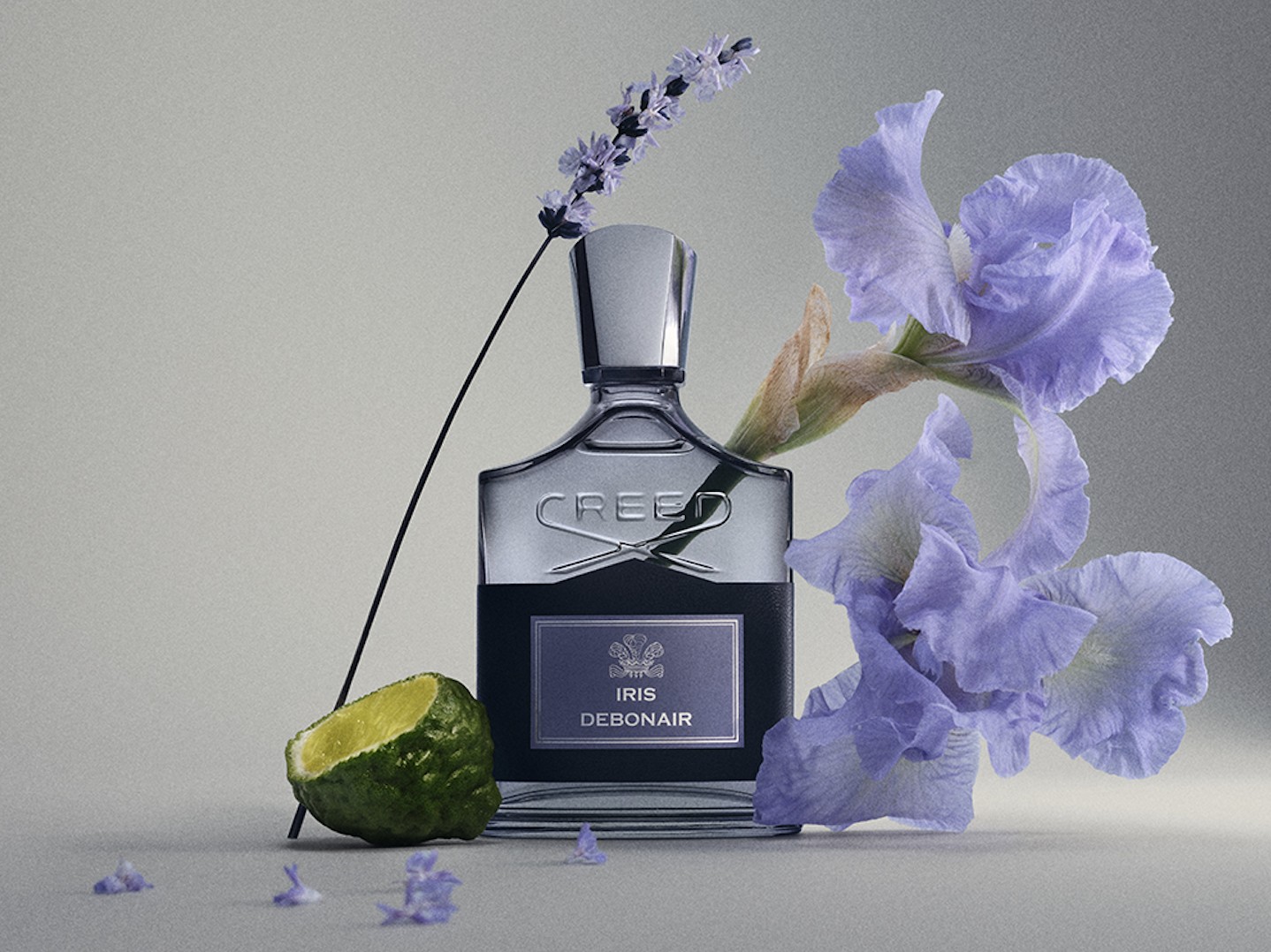 The Creed Iris Debonair bottle beside lavender, iris and a bergamot half