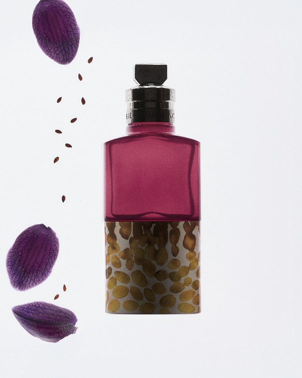 The Velvet Violet bottle with a deep purple top and a sesame-patterned base, with violet petals and sesame seeds